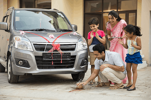 A happy Indian family celebrating their new silver car with traditional ritual setup