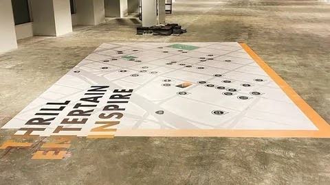 Custom floor decal applied on a walkway displaying the text "THRILL ENTERTAIN INSPIRE"