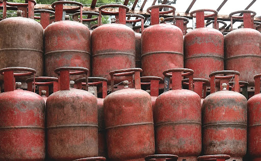 Red LPG cooking gas cylinders stacked together representing domestic LPG supply and monthly price fluctuations in Delhi.