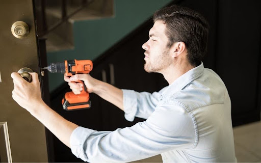 Professional locksmith in Reseda using a power drill to install or repair a door lock mechanism